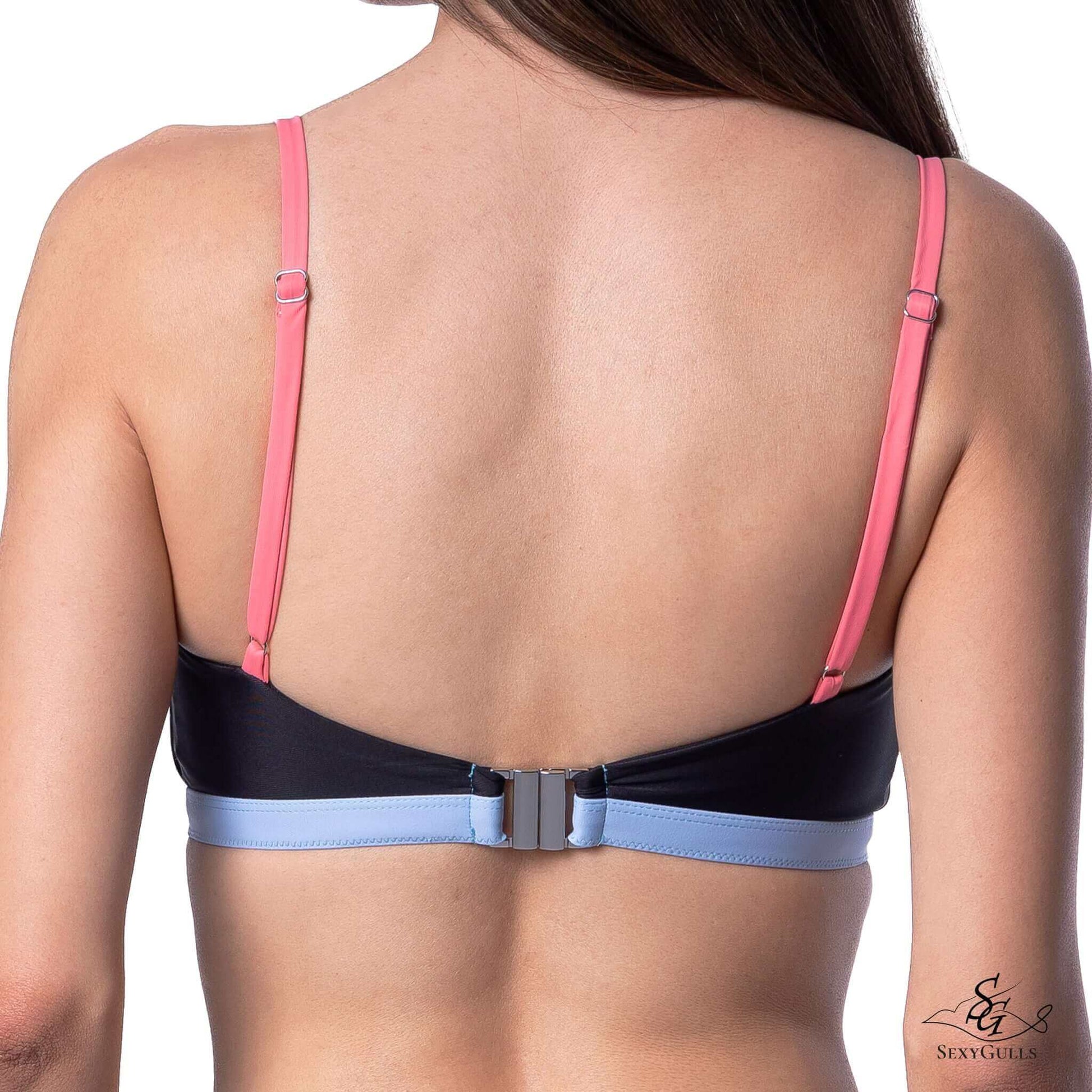 Zoomed in back view of woman in three-toned black, pink, blue bikini top with metallic clasps and slider buckle.